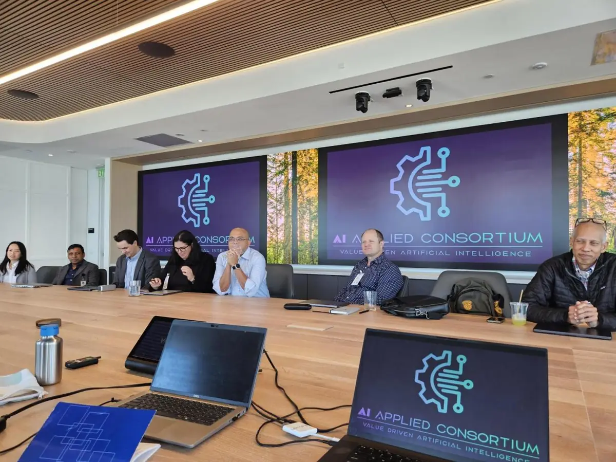 Practitioners around a working-session boardroom table with the consortium framework on screen